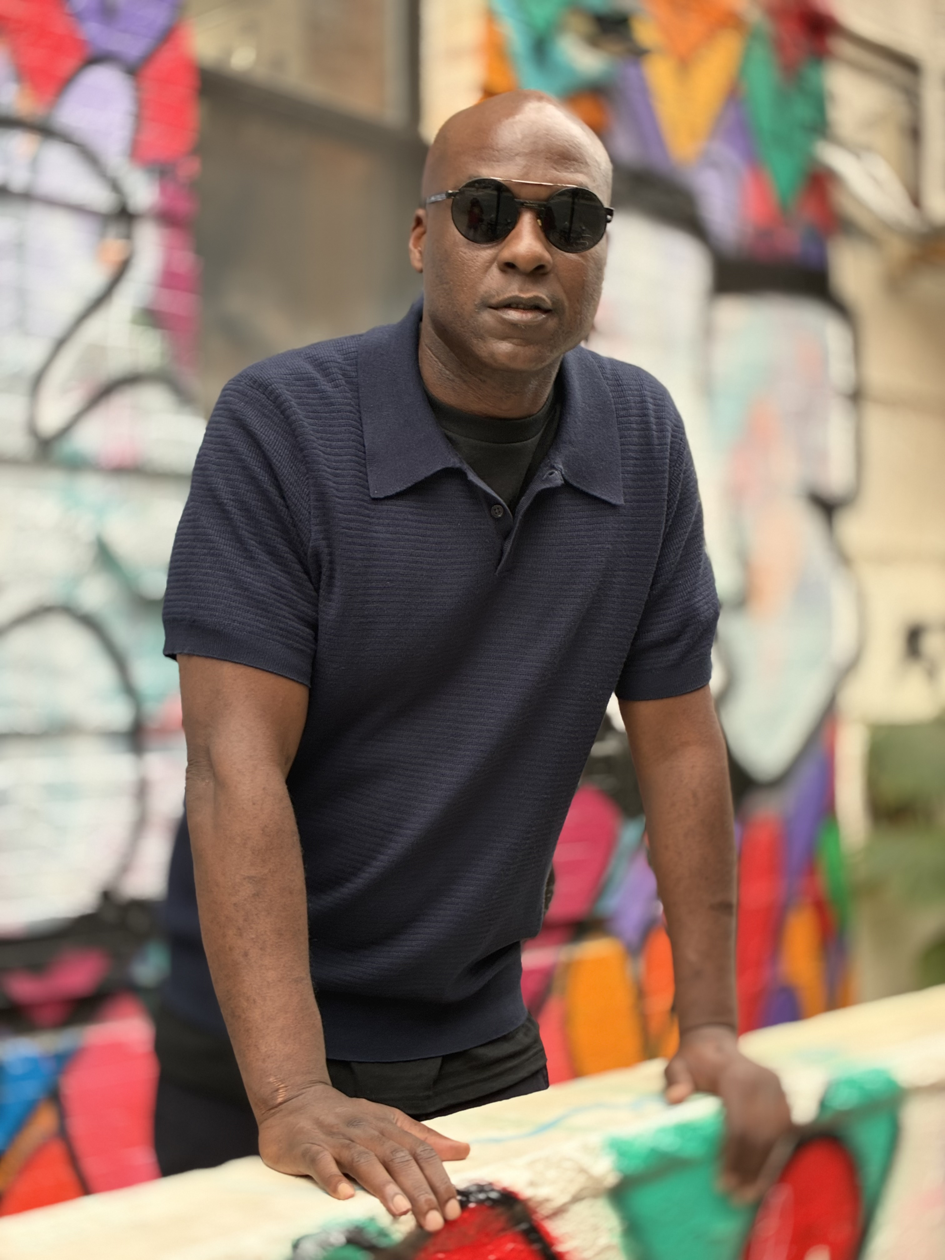 Josephe “Pop” Buchanan standing in front of a colorful mural